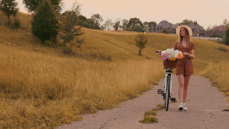 Lens-flare:-smiling-happy-woman-in-short-dress-is-riding-a-bicycle-with-a-basket-and-flowers-in-the-park-with-green-trees-around-during-the-dawn.-Slowmotion-shot